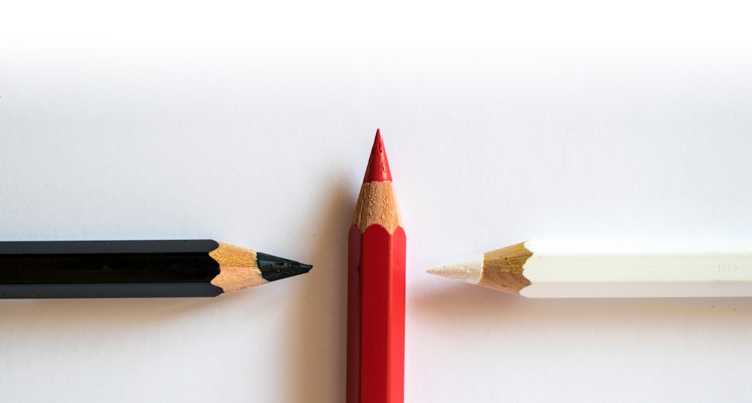 two pencils sitting next to each other on a white surface