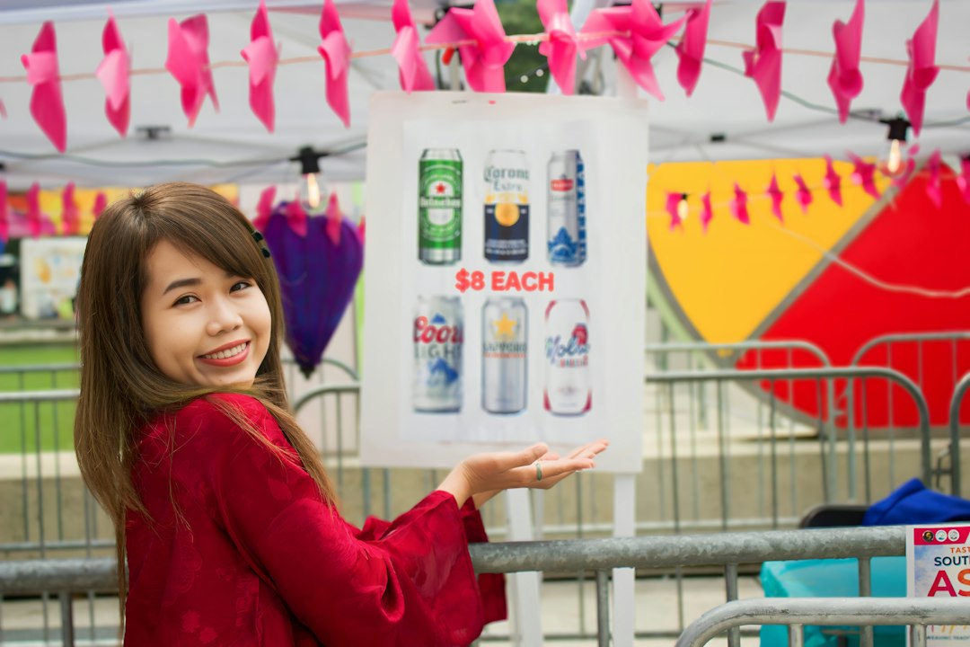 Woman in red gestures towards a sign with beverage cans